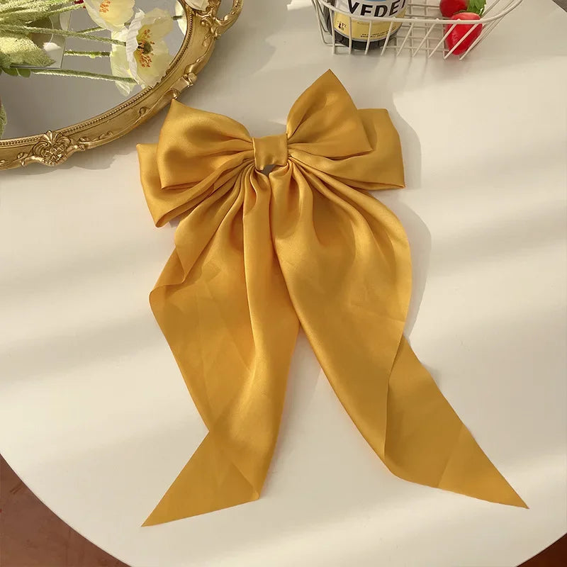 Gold bow hair accessory on a white surface with decorative items in the background