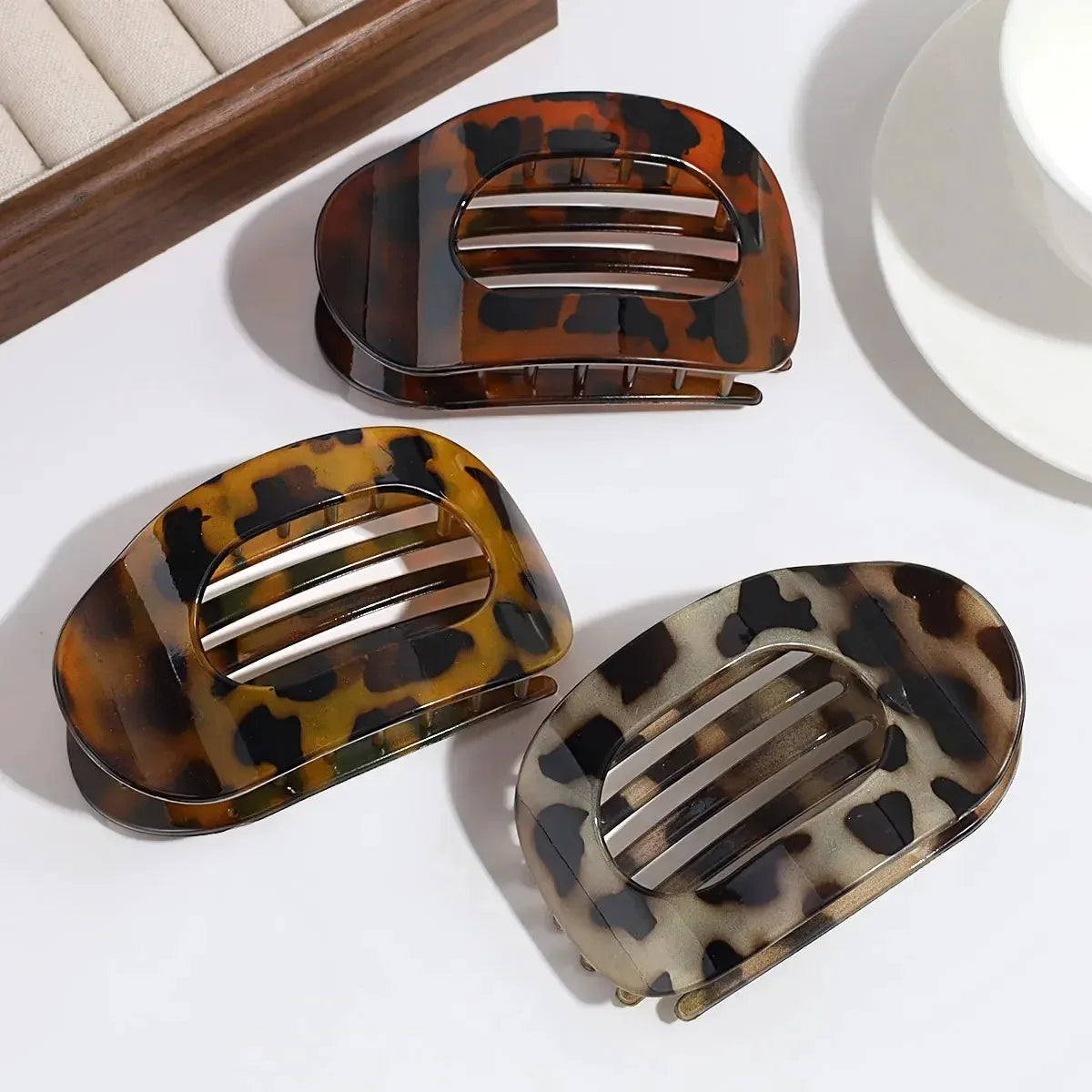 Three tortoiseshell patterned hair clips on a white surface