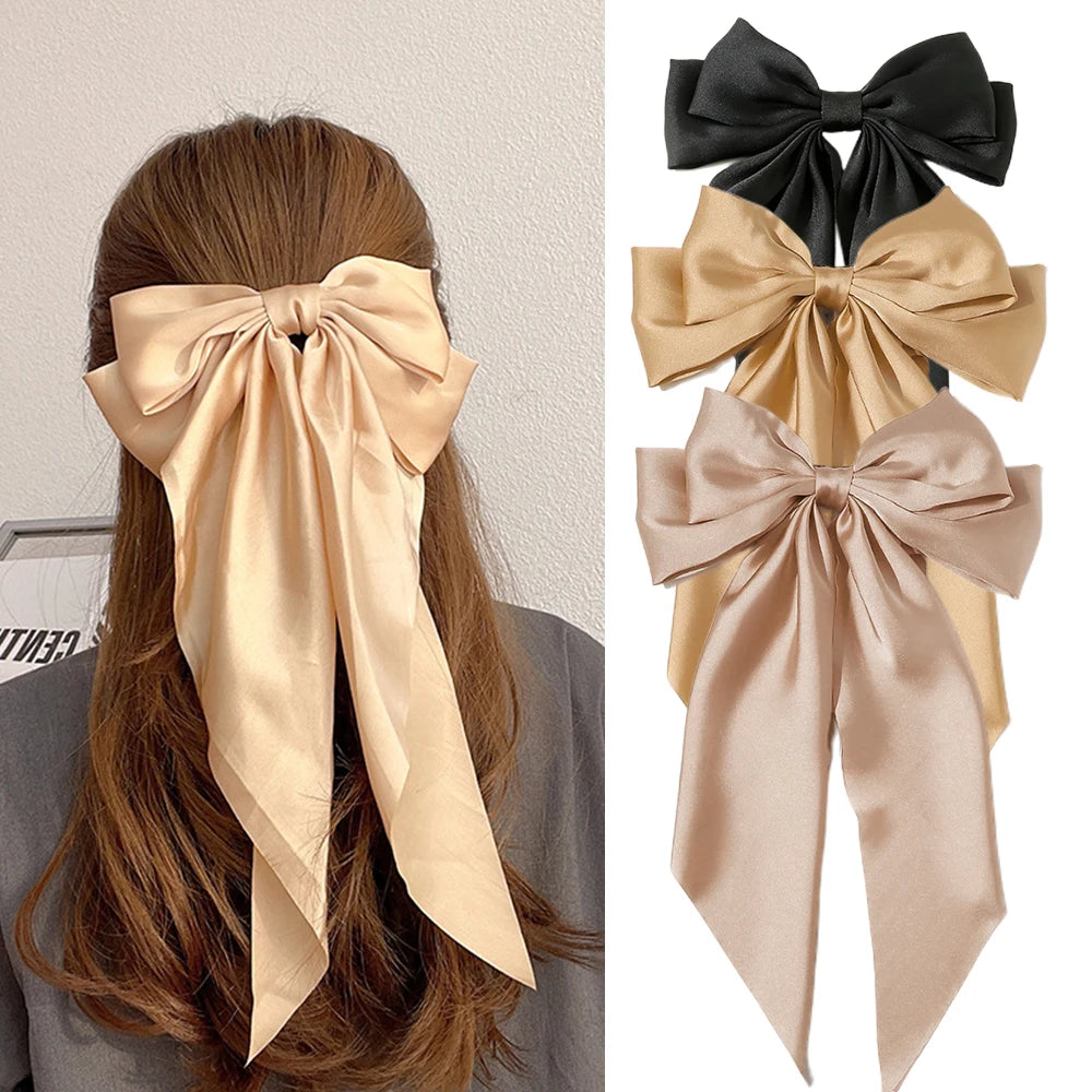 Beige hair bow accessory worn by a person with long brown hair, shown on a white background.