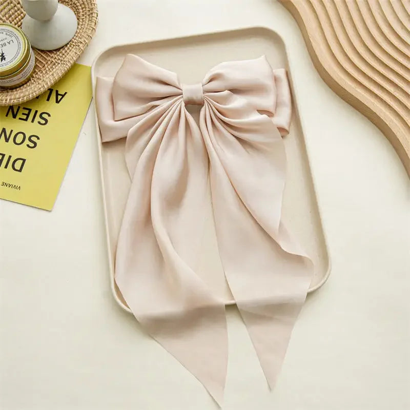 Beige bow tie on a light beige surface with a book and decorative items.