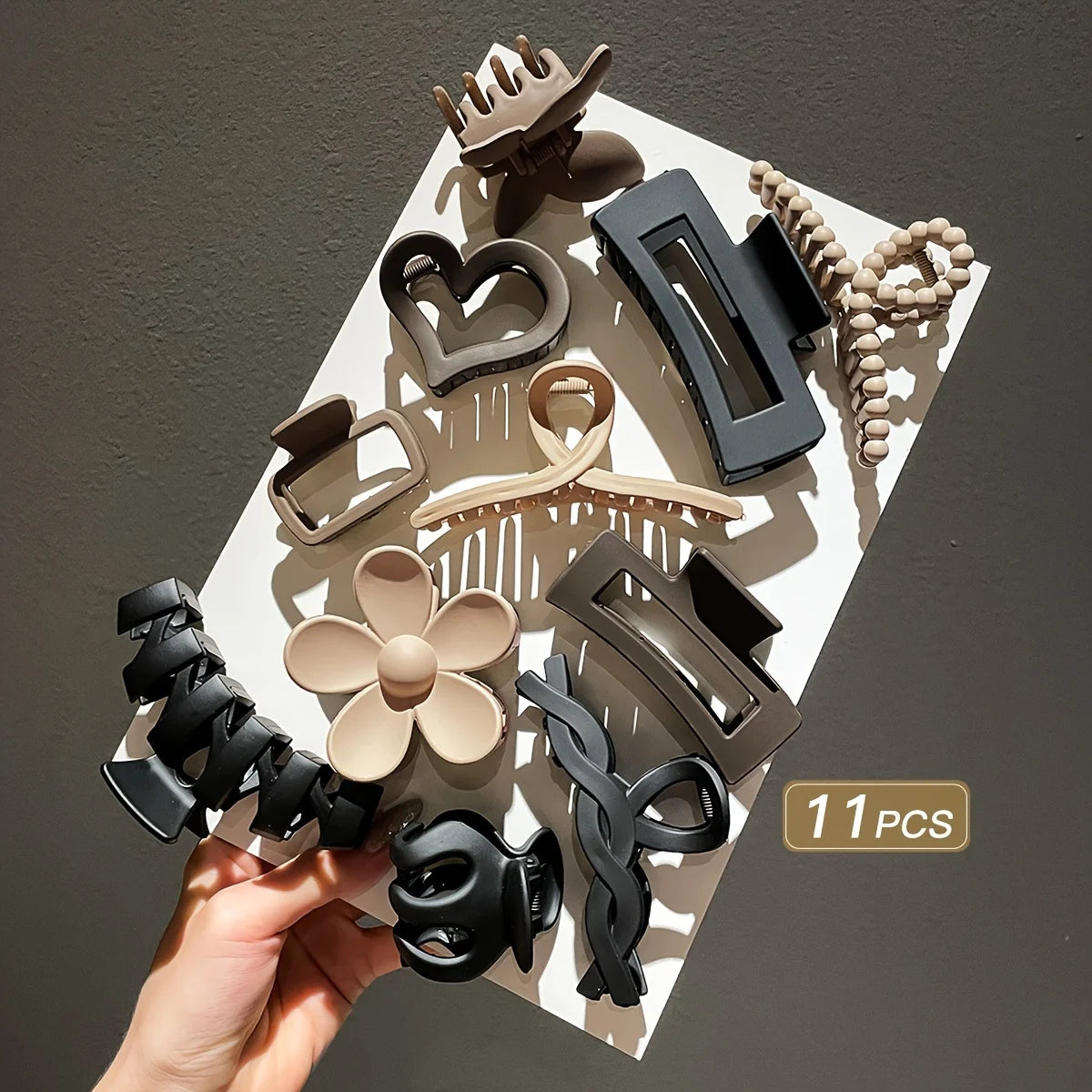 Set of 11 hair accessories including clips and bands on a white surface with a gray background.