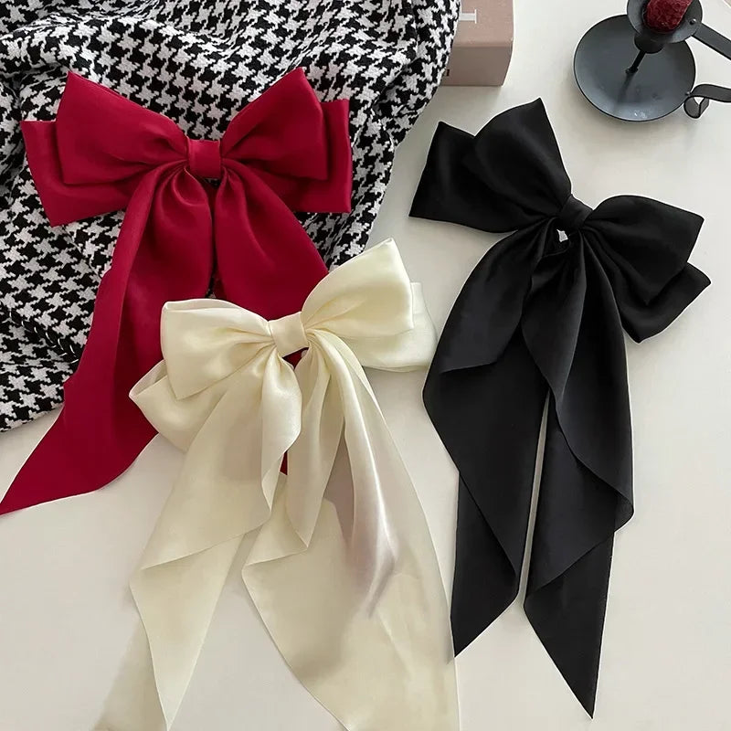 Three large fabric bows in red, white, and black on a white surface.