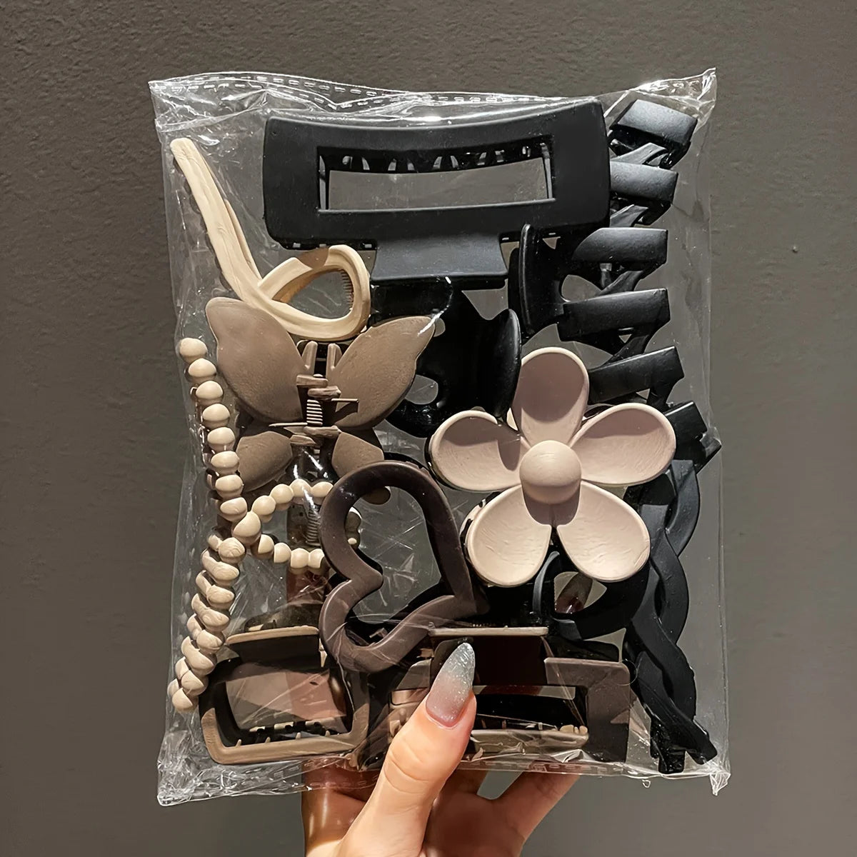 Packaged hair clips with floral and geometric designs held by a hand against a plain background