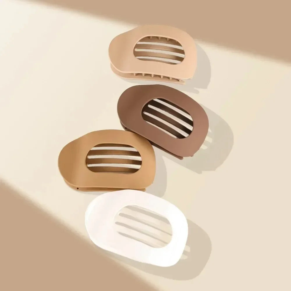 Set of four hair clips in beige, brown, and white on a light background