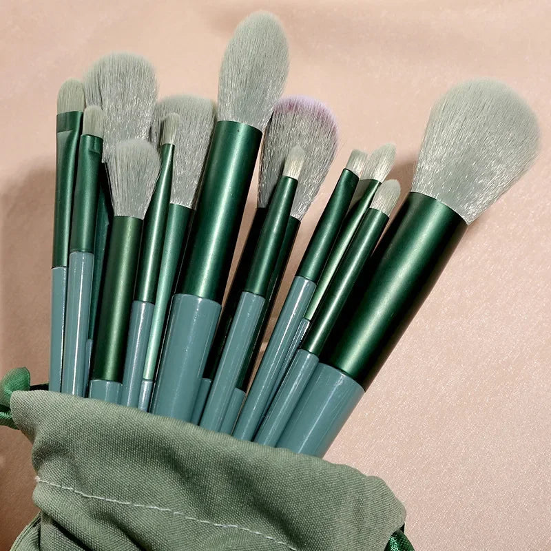 Set of makeup brushes with green handles and gray bristles in a green case on a beige background