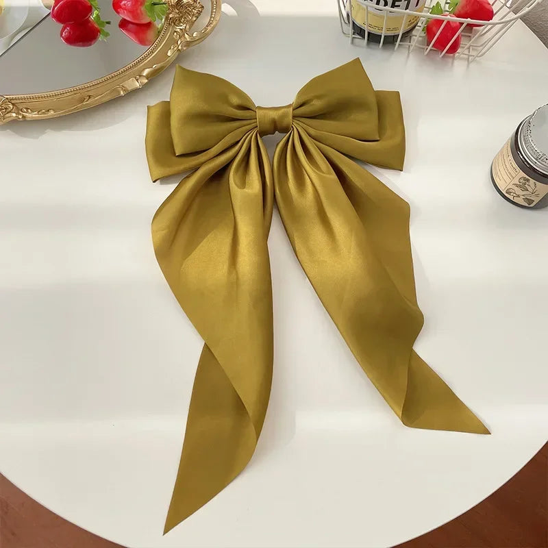 Large mustard yellow bow on a white surface with decorative items in the background.