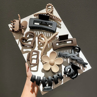 Collection of various hair clips on a white square with a hand holding it against a dark background
